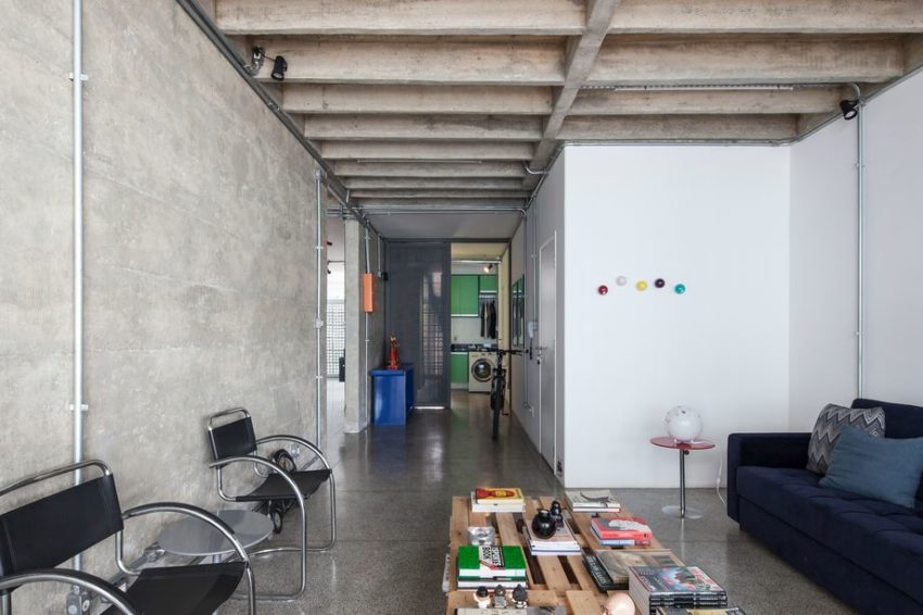 Deze industriële woonkamer van een appartement uit 1961, is ontworpen door SuperLimão - gekenmerkt met zowel een betonnen vloer als een betonnen muur.
