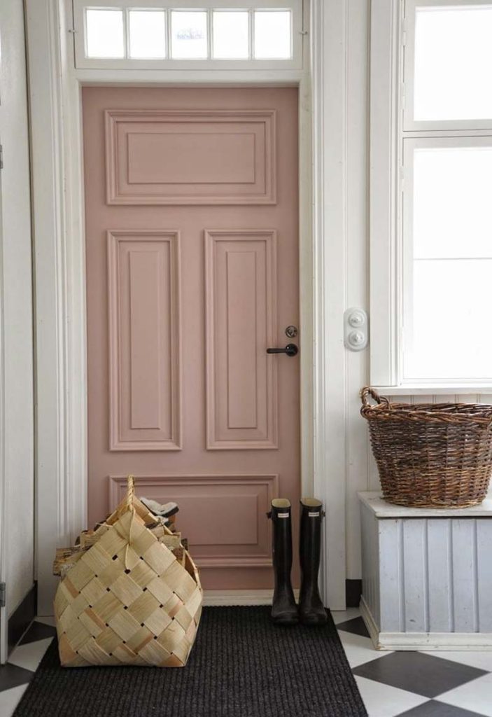 De zwarte deurklink met een rond ontwerp past geweldig bij de oud roze paneeldeur.
